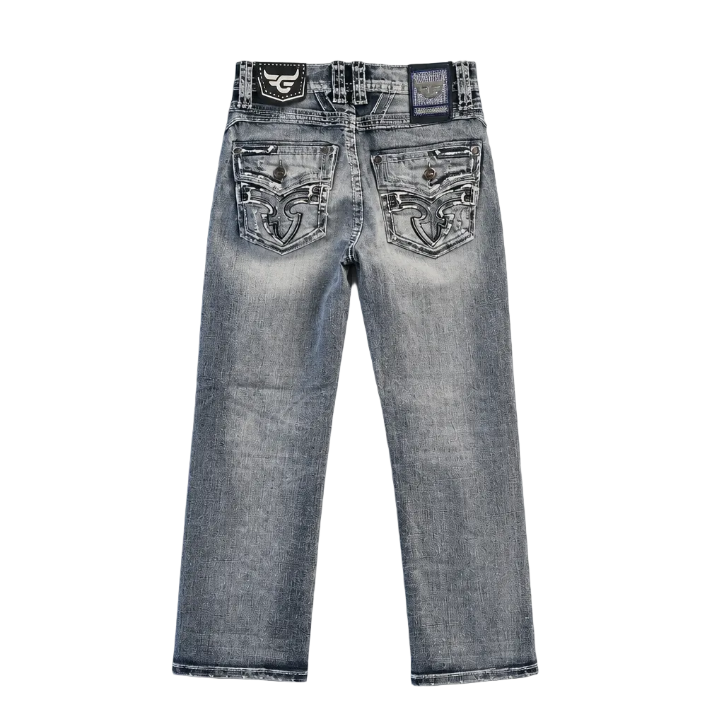 Back view of light-wash blue denim jeans with ornate silver and black embroidered patches on the back pockets, photographed flat on a light gray background.